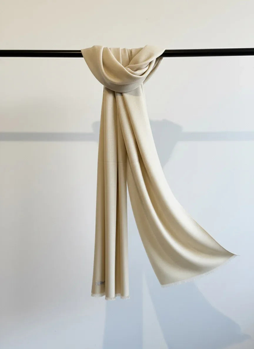Beige scarf draped over a black rod against a light background