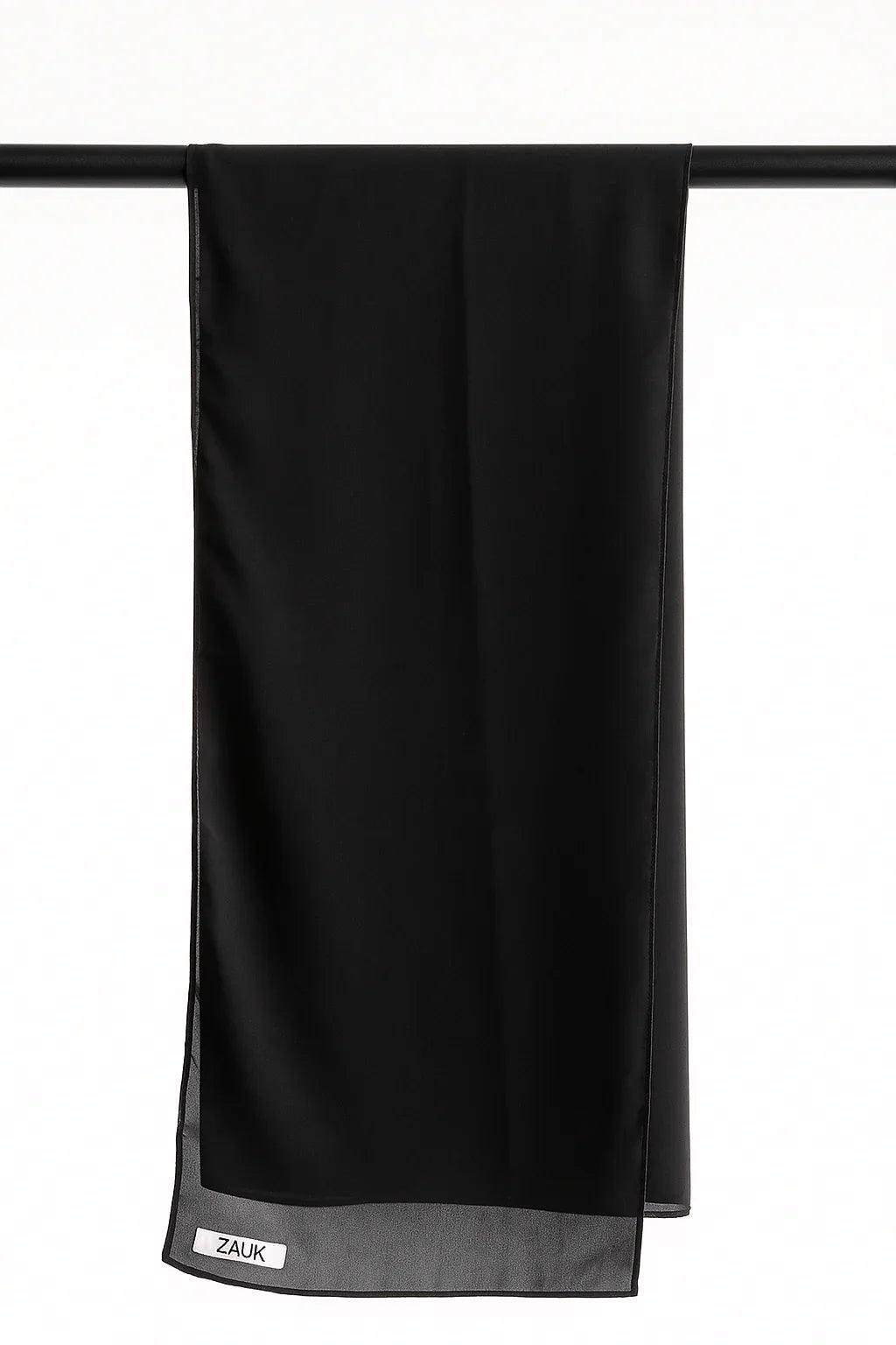 Black scarf hanging on a rack against a white background