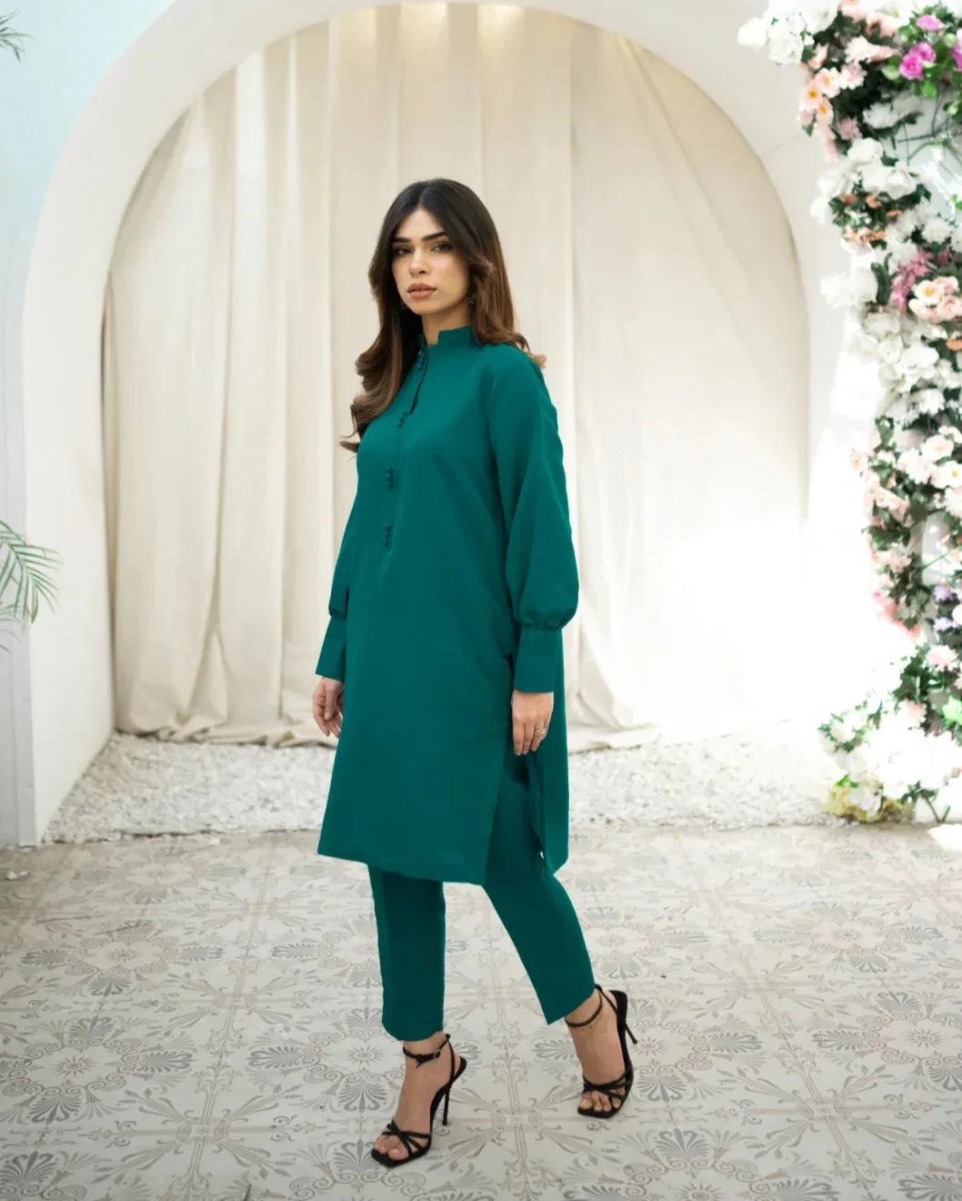 A woman wearing a green two-piece indian rawsilk dress consisting of a shirt and trousers.
