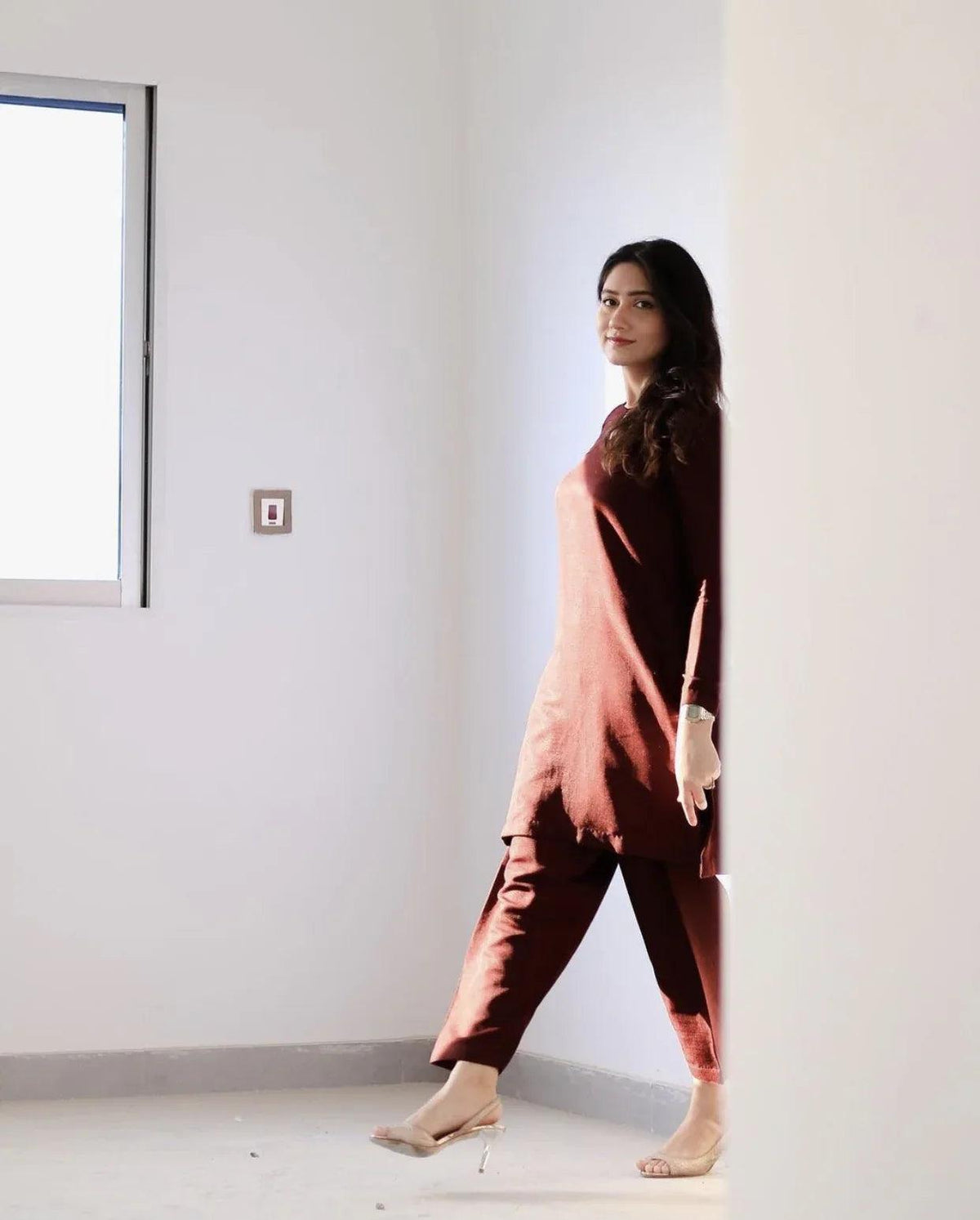A women wearing a maroon two piece dress which includes a shirt and culotte.