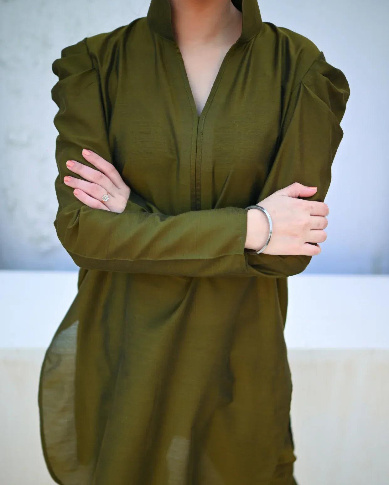 Person wearing a green dress with puffed sleeves against a neutral background