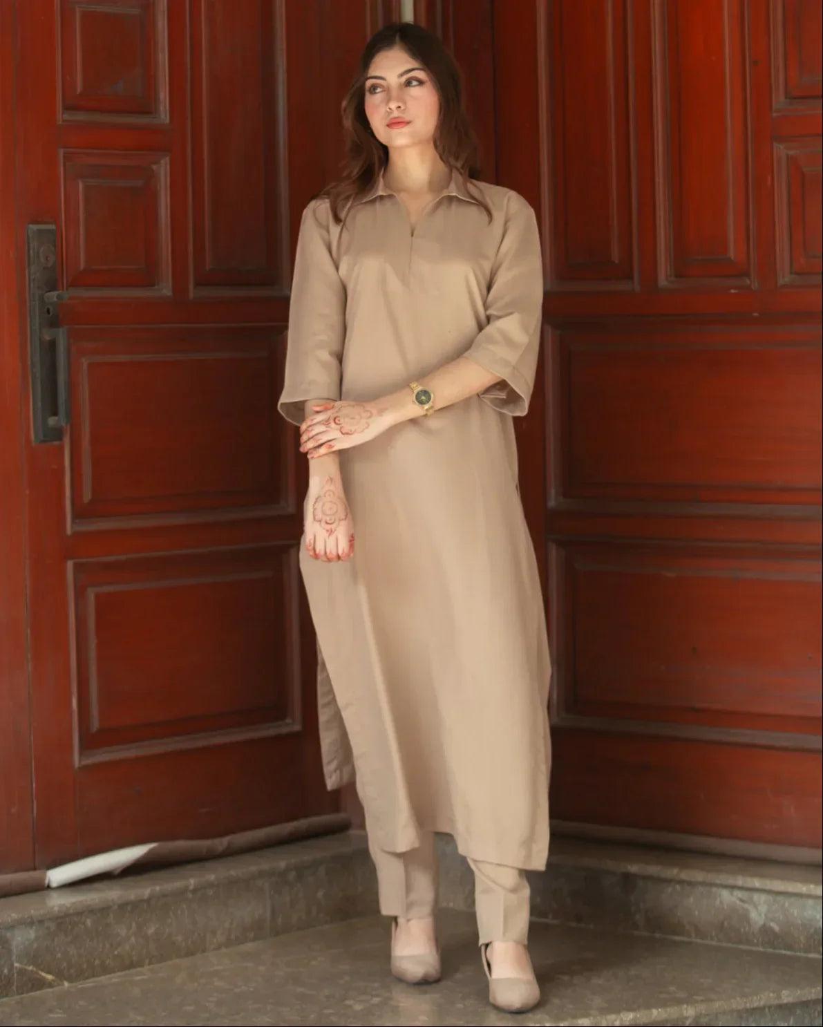 A woman in a Phone Dress stands in front of large wooden doors with a thoughtful expression.