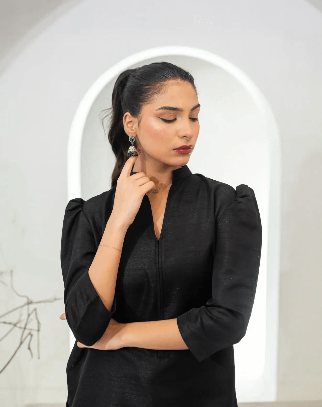 Woman wearing a black dress with puffed sleeves in a minimalistic setting