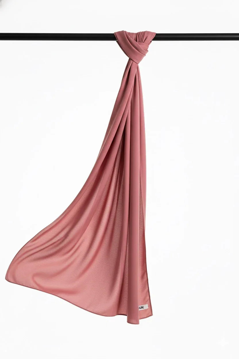 Tea Pink scarf draped over a black rod on a white background