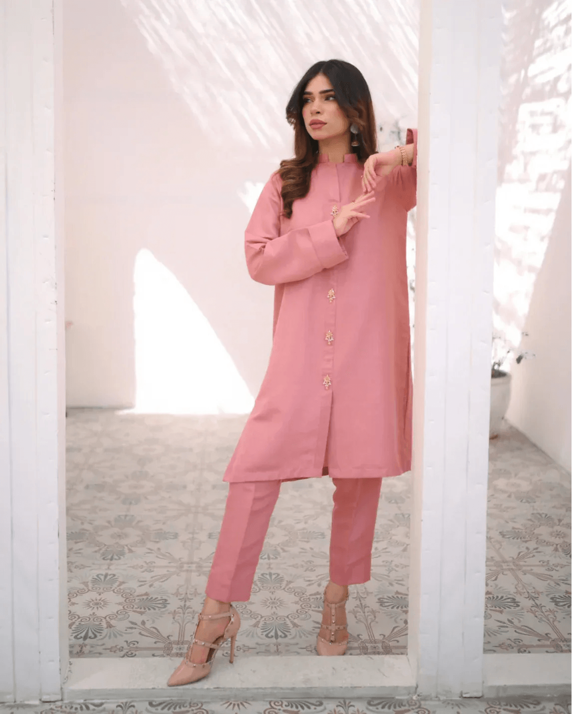A woman wearing a pink two-piece indian rawsilk dress consisting of a shirt and trousers.