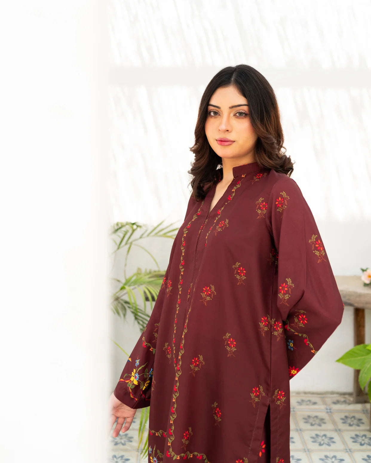 Woman wearing a maroon floral dress against a white background