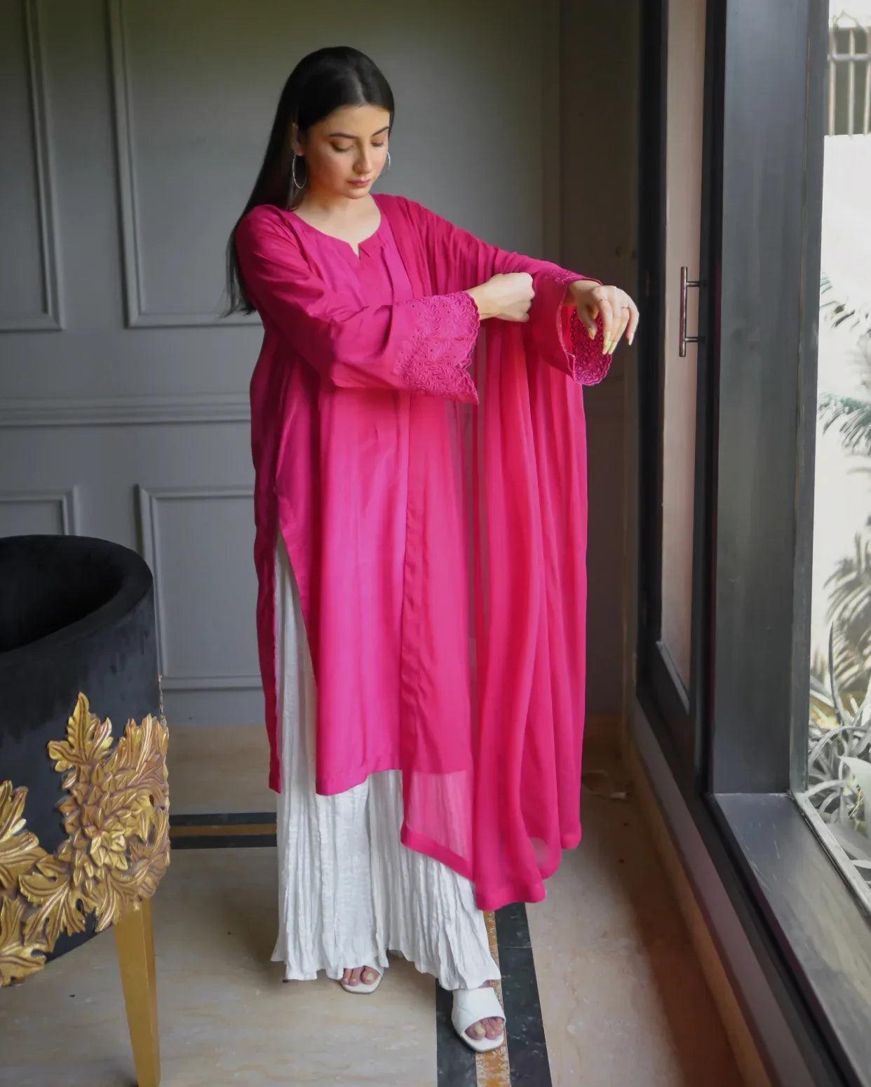 Women wearing a three piece pink color dress which includes a shirt with embroidery on sleeves, dhaka lehenga and a chiffon dupatta.