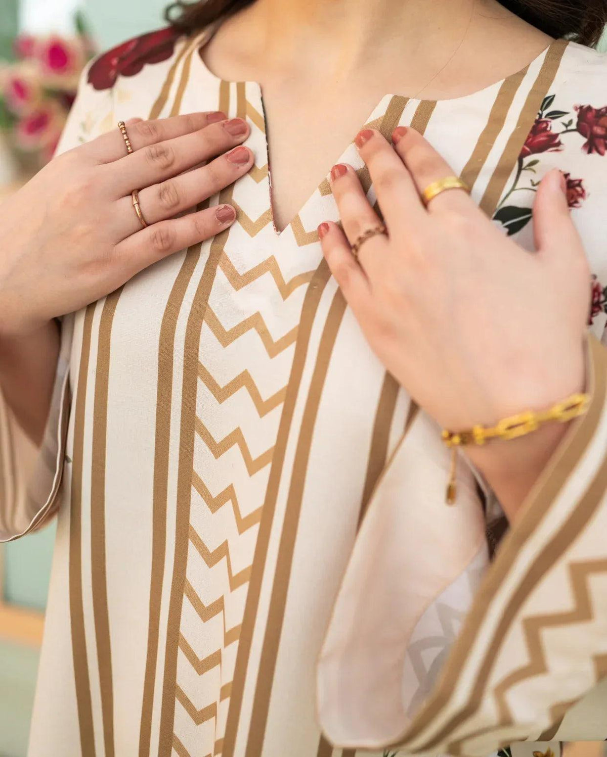 Close-up of a women wearing a patterned printed top in pastel color with visible jewelry.