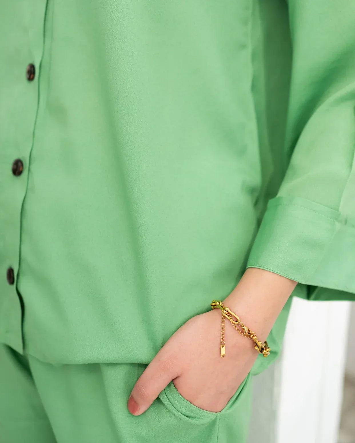 women wearing a green solid western outfit with a gold bracelet on a blurred background