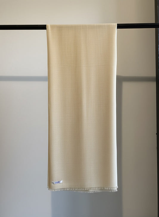Beige scarf hanging on a black rack against a white wall