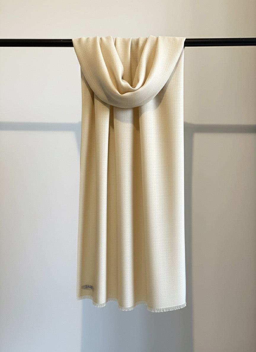 Beige scarf draped over a black rod against a light gray wall.
