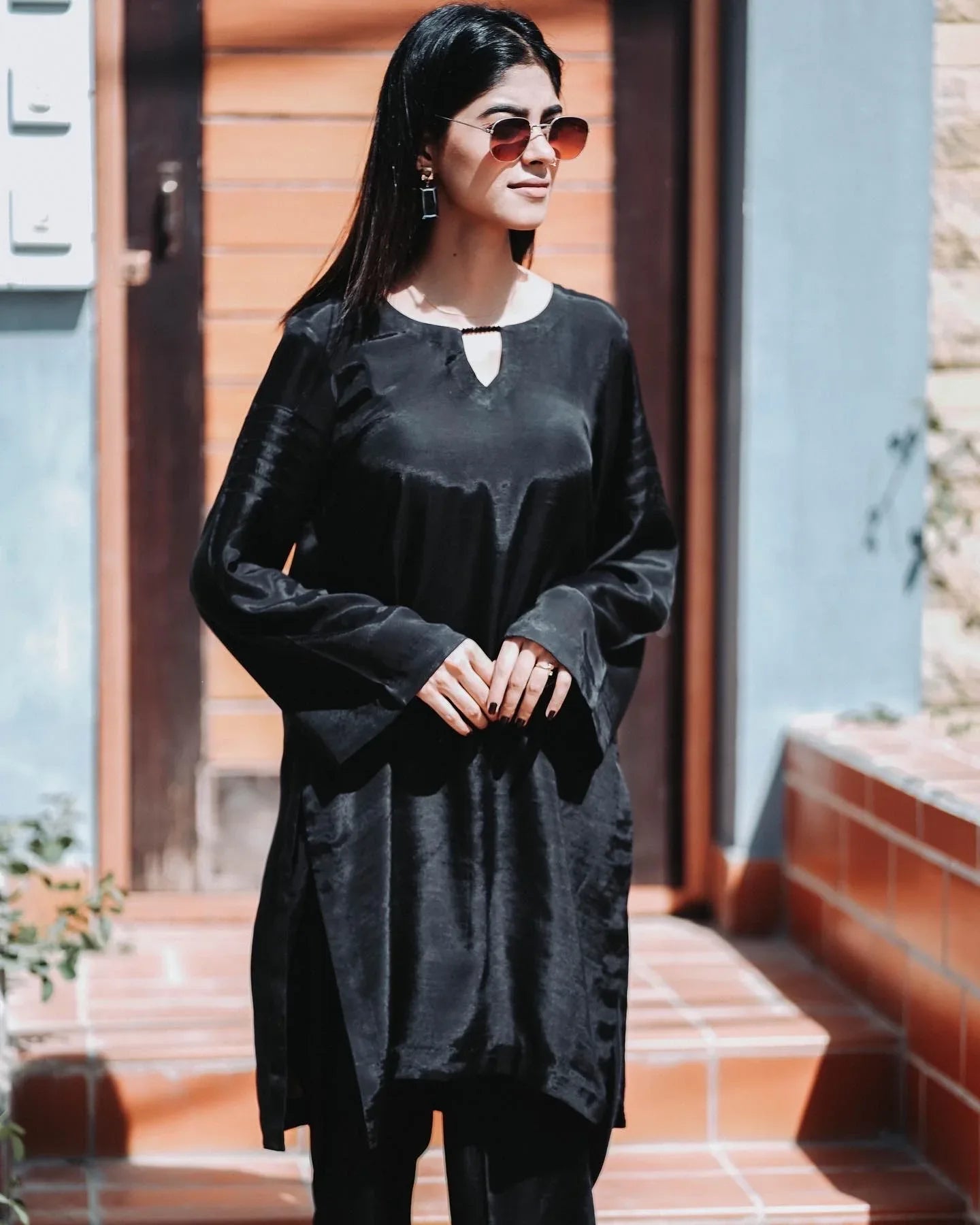 Women wearing a black outfit with a big door in background.