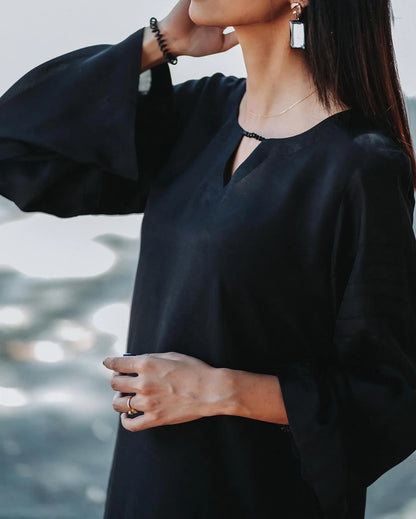 Women wearing a black outfit with blurred background.