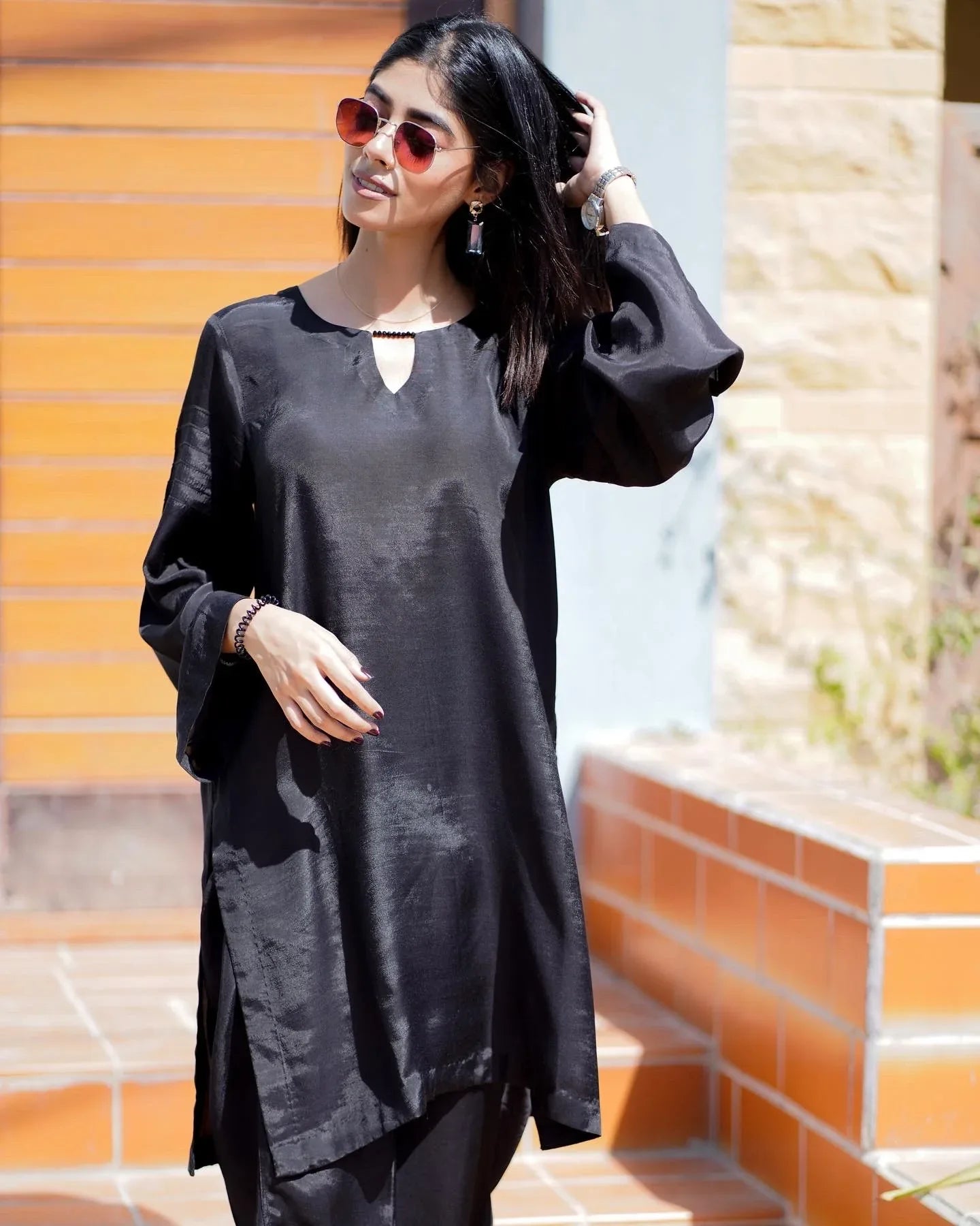 Women wearing a black outfit with a big door in background.