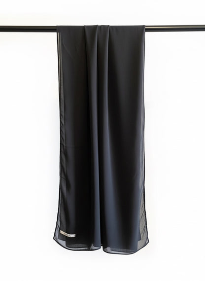 Black scarf hanging on a rod against a white background