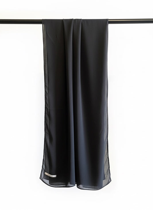 Black scarf hanging on a rod against a white background