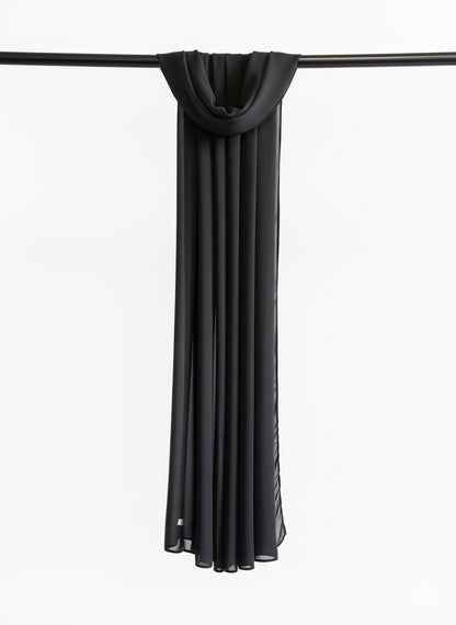 Black scarf draped over a black rod on a white background