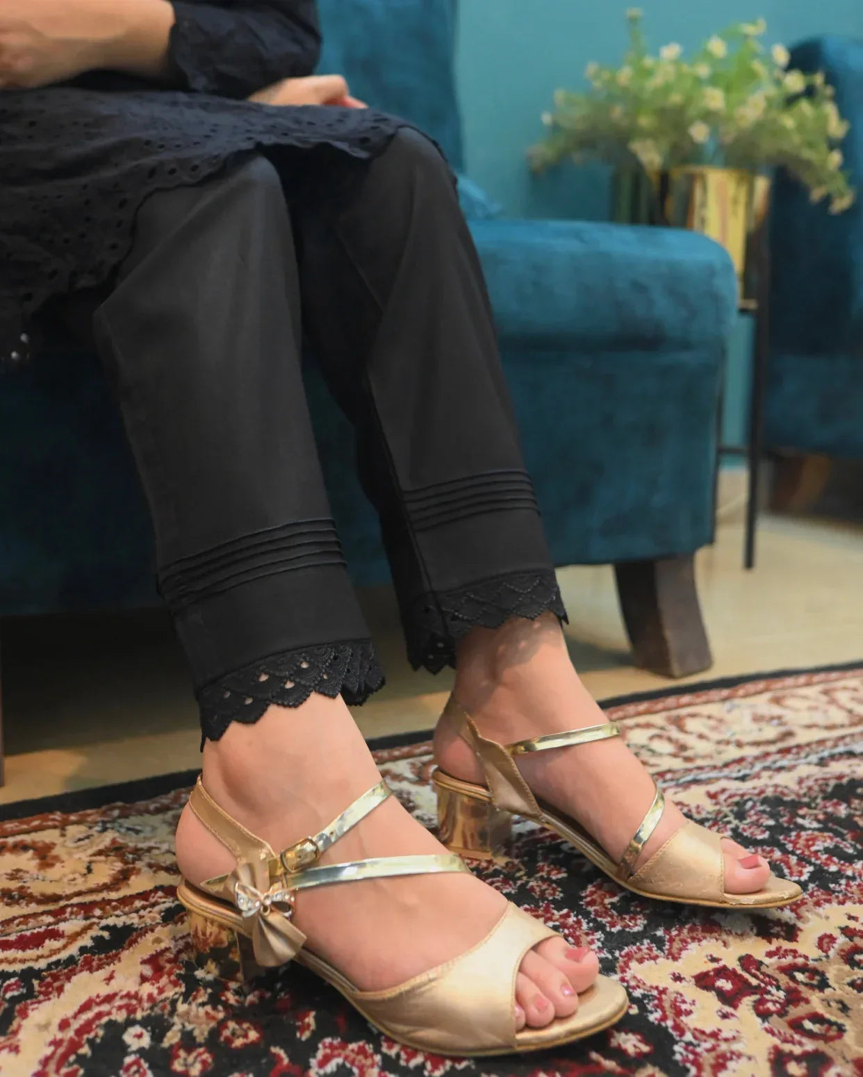 Person wearing a black Trouser with details on bottom in a room with a blue couch.