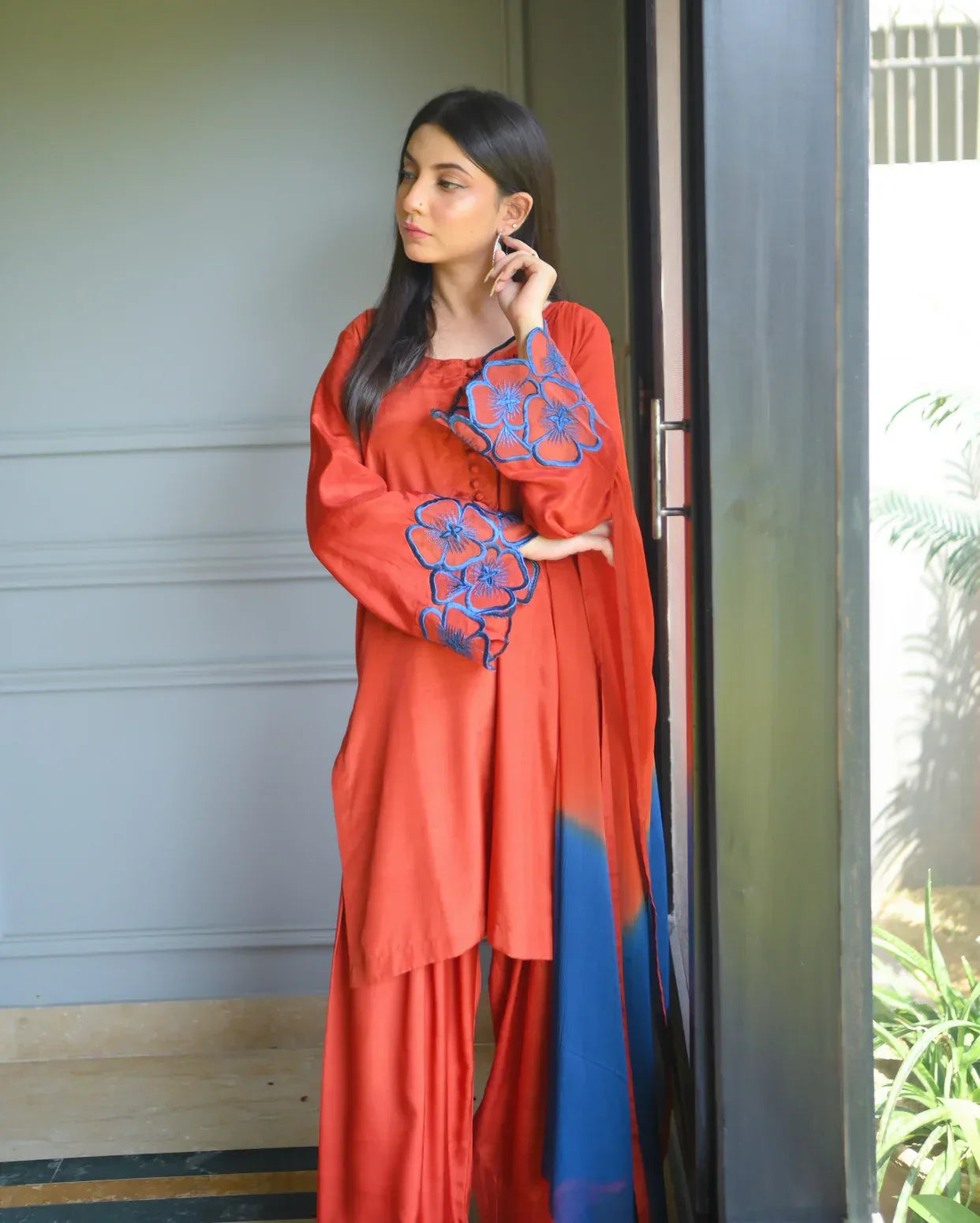 Women wearing a three piece orange dress which includes a Farshi Shalwar kameez with embroidery on sleeves,  and a two tone dyed chiffon dupatta.