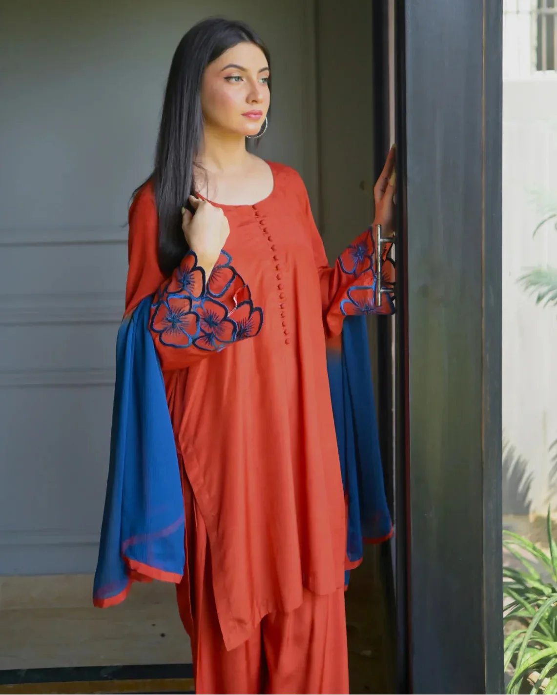 Women wearing a three piece orange dress which includes Farshi Shalwar kameez with embroidery on sleeves and a two tone dyed chiffon dupatta.