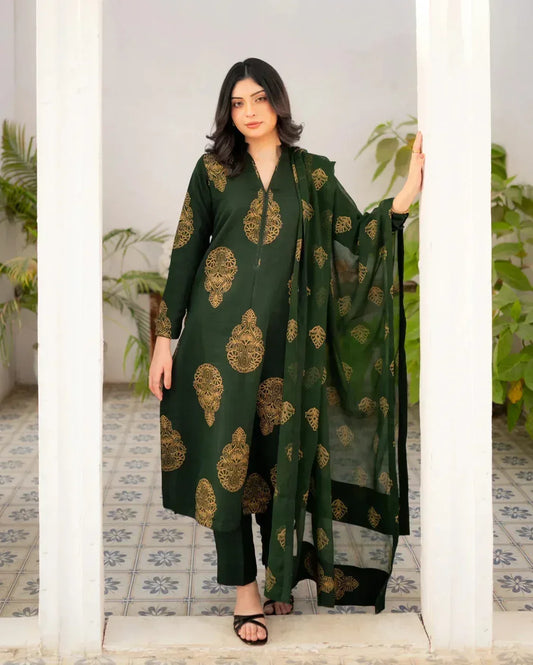 Woman wearing a bottle green traditional three piece dress with gold patterns in an indoor setting.