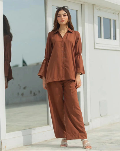 Woman in a brown dress standing in front of a white building with large windows.
