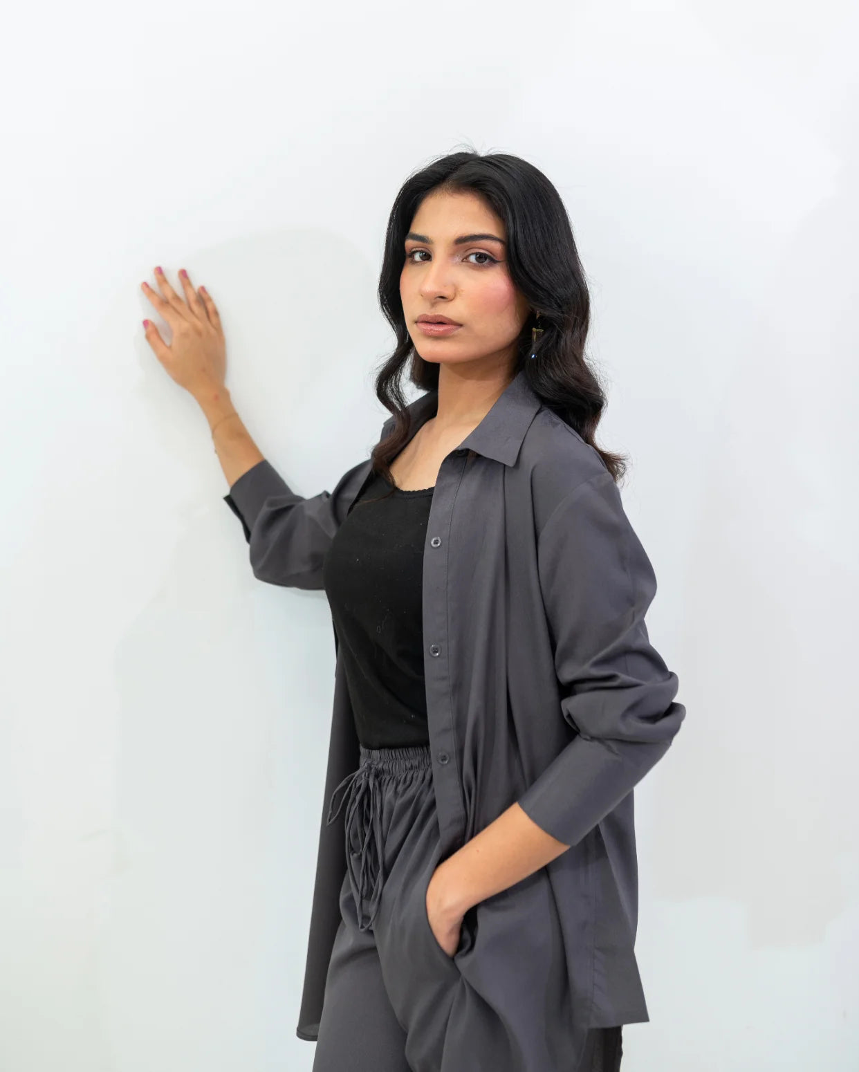 Woman wearing a charcoal gray button down shirt over a black top against a white background
