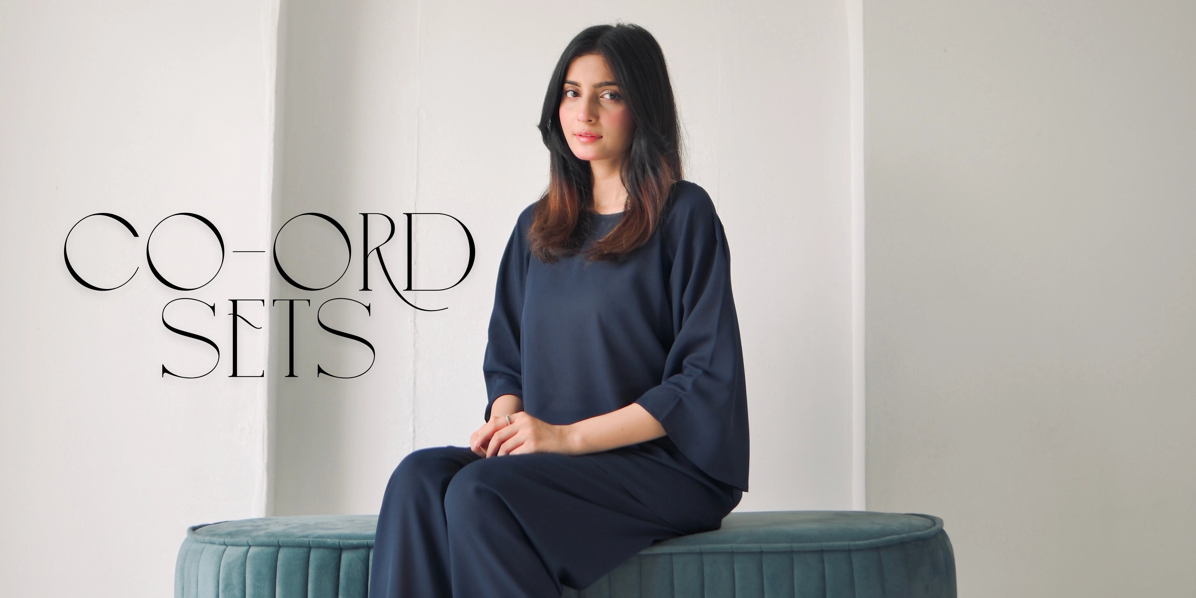 Woman in a navy blue outfit sitting on a teal bench with 'Co-ord Sets' text.