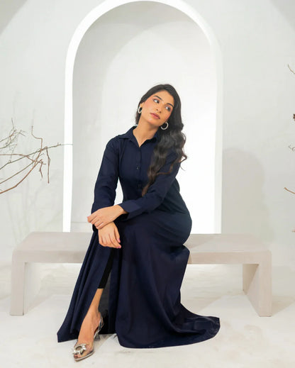 Woman in a navy blue dress sitting on a white bench with a white archway in the background