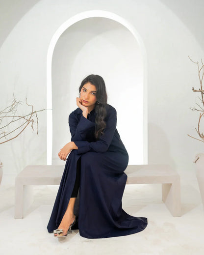 Woman in a navy blue dress sitting on a white bench with a white archway in the background