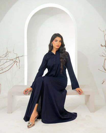 Woman in a navy blue dress sitting on a white bench with a white archway in the background