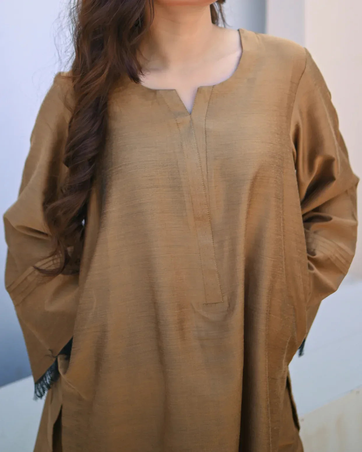 Woman wearing a beige long-sleeve top against a light background