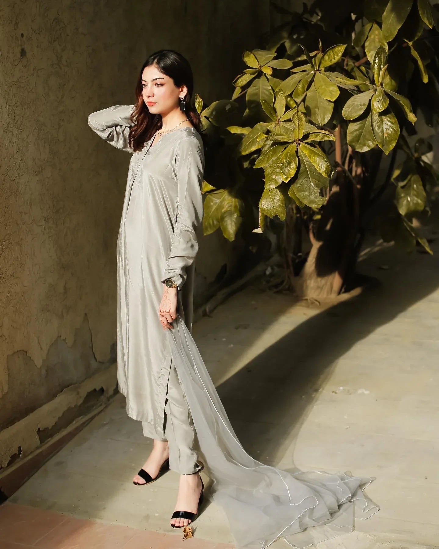 Women wearing a grey three piece dress with a tree in the background.