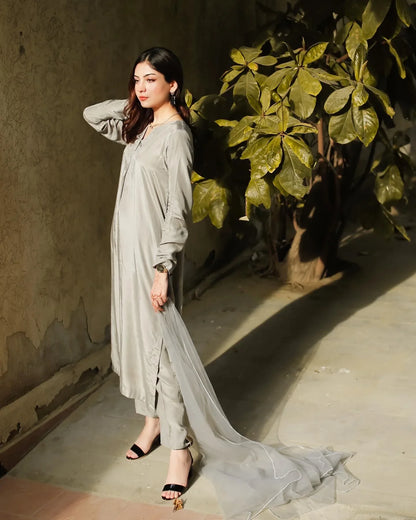 Women wearing a grey three piece dress with a tree in the background.