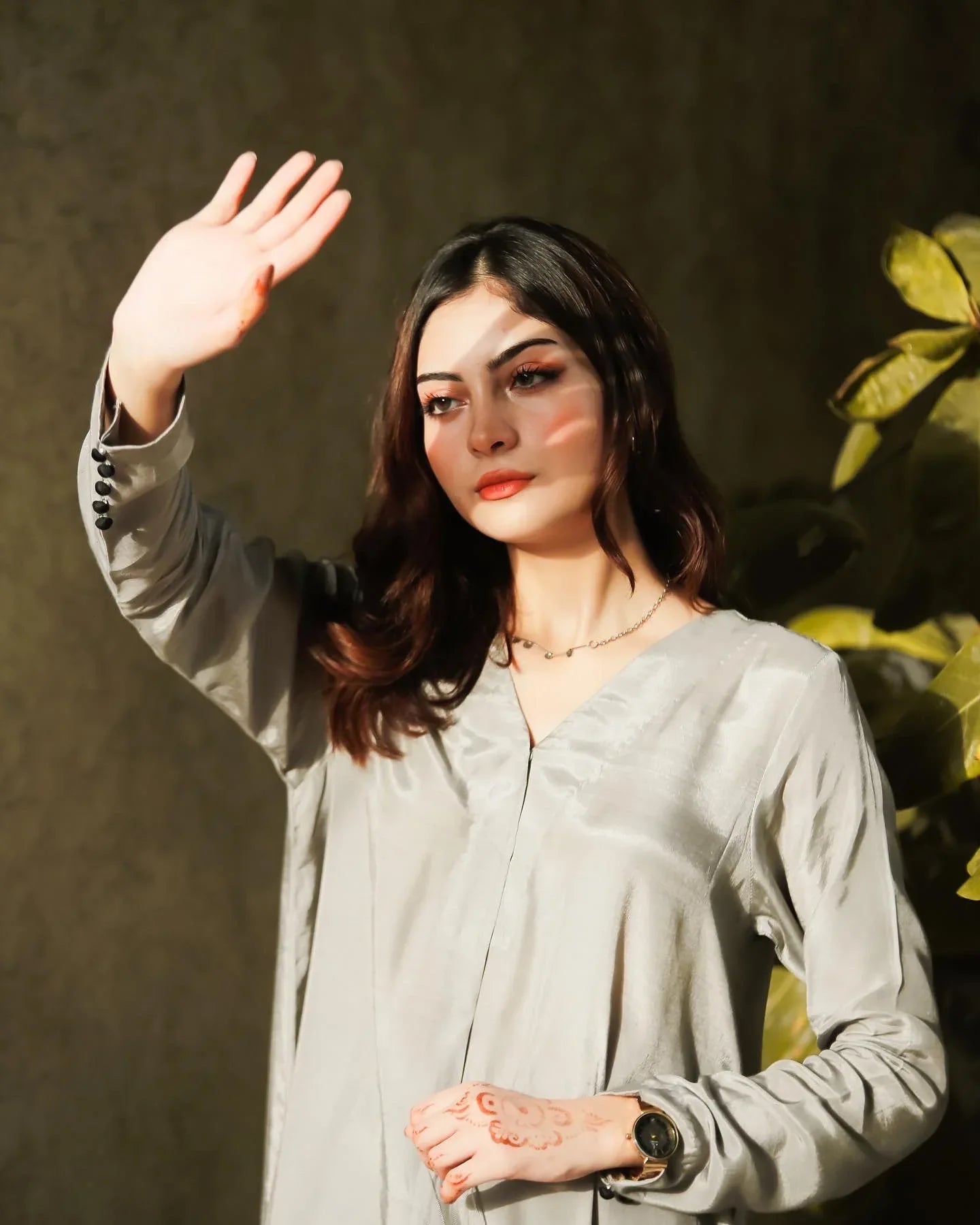 Women wearing a grey dress with a tree in the background.