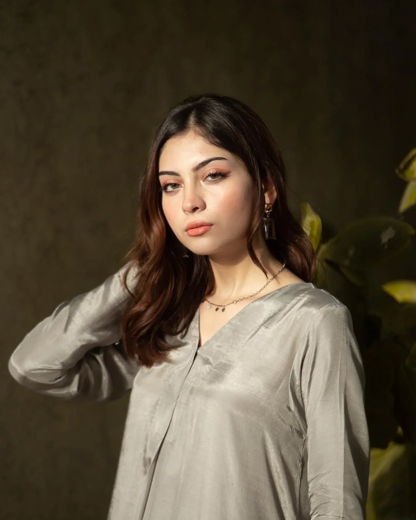 Women wearing a grey dress with leaves in the background.