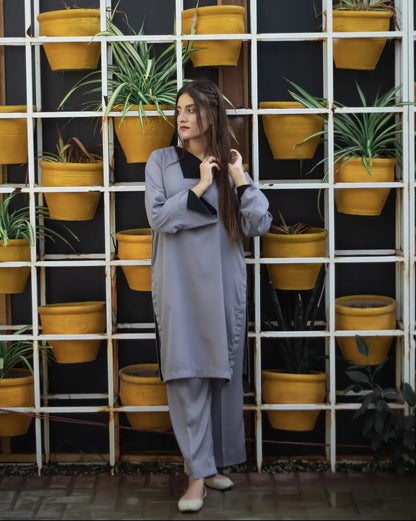 Woman in a gray dress stands in front of a grid of vibrant yellow pots with green plants. 