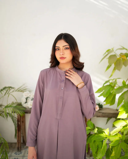 Woman wearing a mauve dress standing in a room with plants