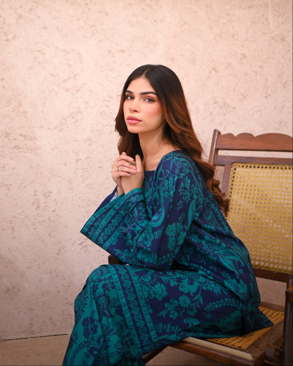 Women sitting on a chair wearing a floral printed two piece dress.