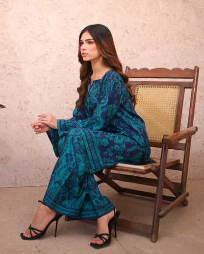 Women sitting on a chair wearing a floral printed two piece dress which includes a shirt and culotte.