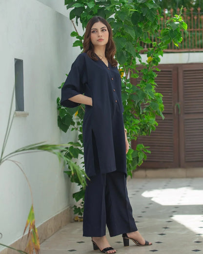 Woman in a navy blue Dress standing outdoors with greenery in the background