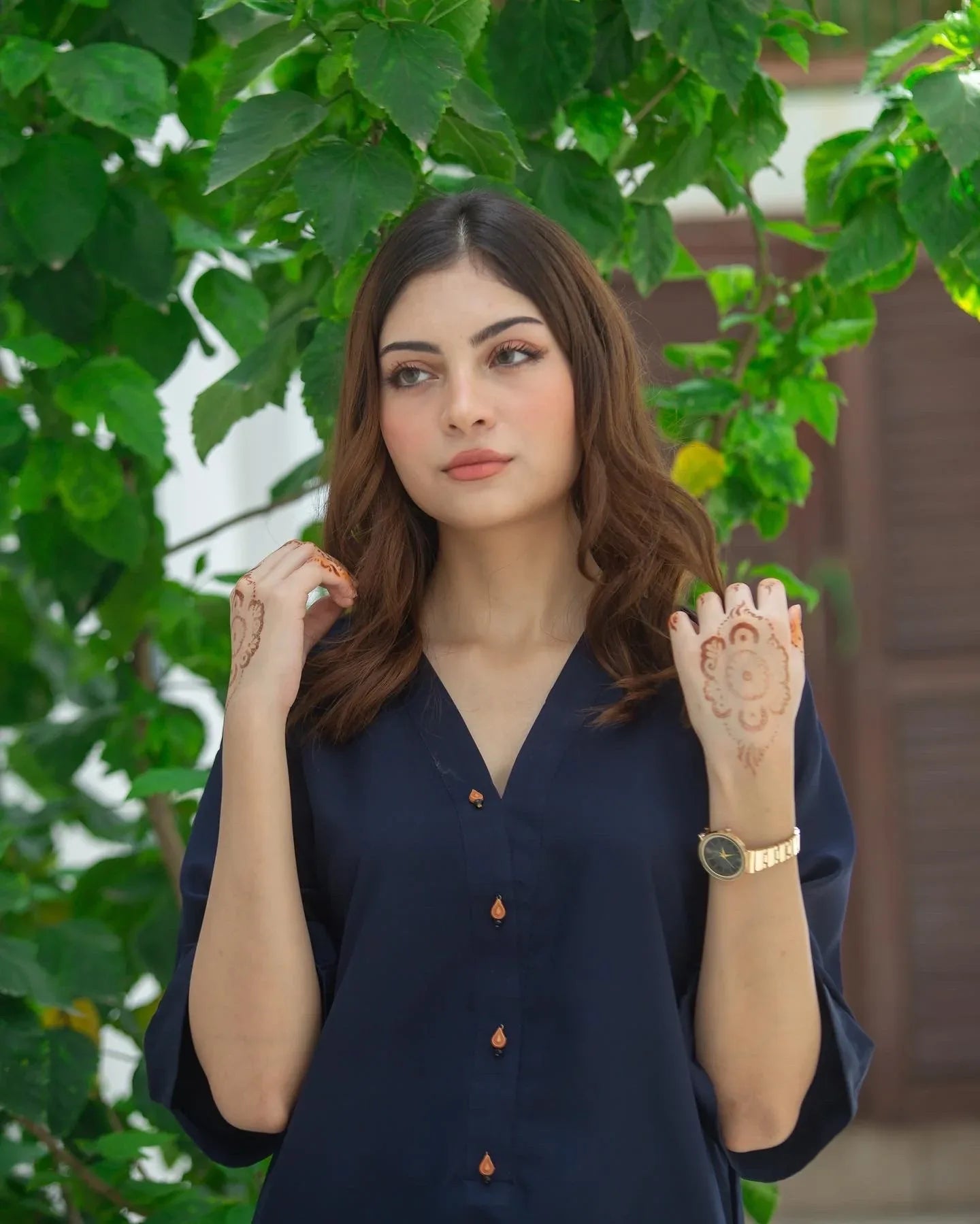 Woman in a navy blue outfit standing outdoors with greenery in the background