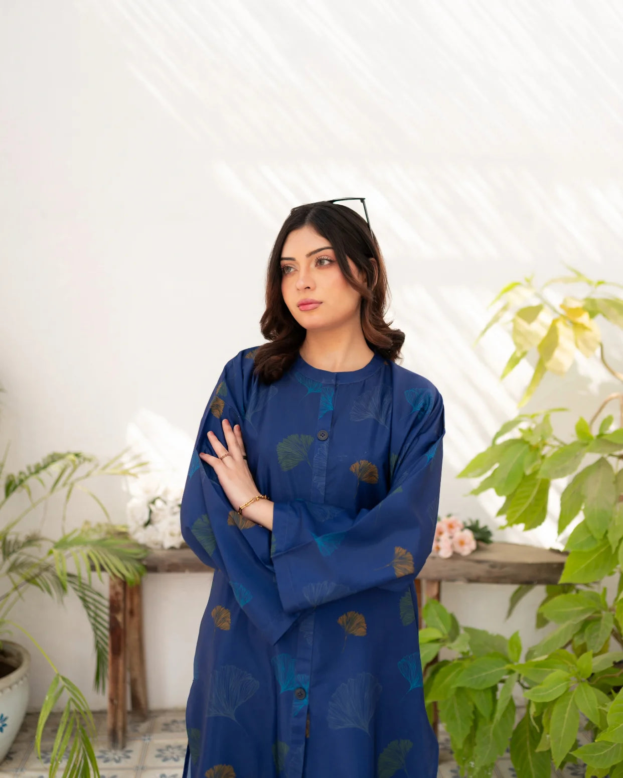 Woman wearing a navy blue dress with floral prints in a room with plants
