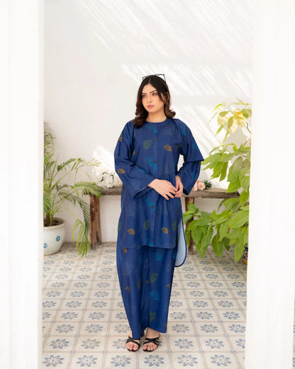 Woman wearing a navy blue traditional printed in a room with plants and a tiled floor.