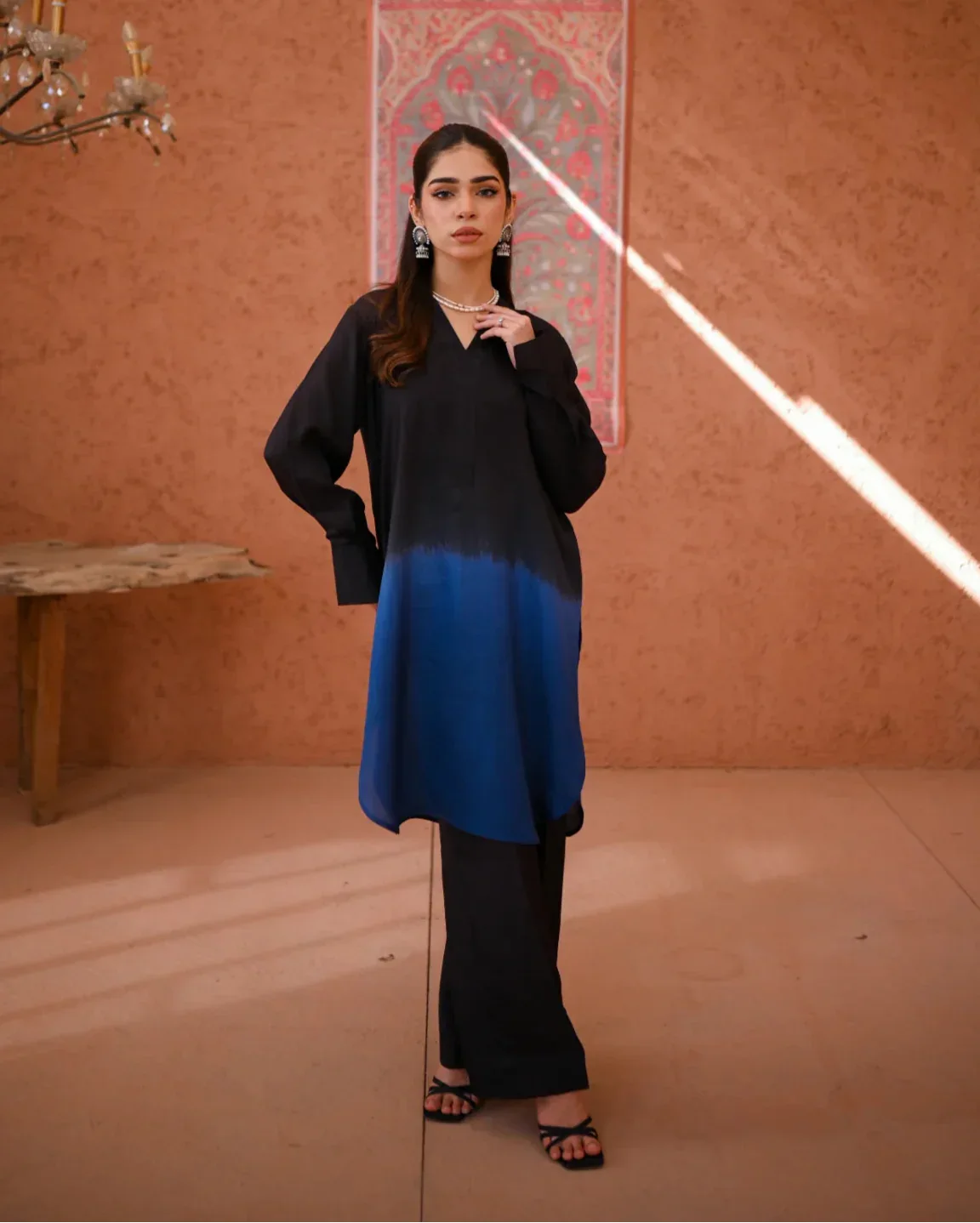 A woman wearing a two-piece Rawsilk dress with an Ombre shirt and culotte, standing in a room with earthen tones.