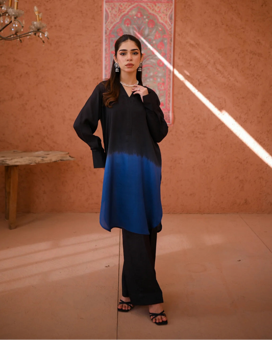 A woman wearing a two-piece Rawsilk dress with an Ombre shirt and culotte, standing in a room with earthen tones.
