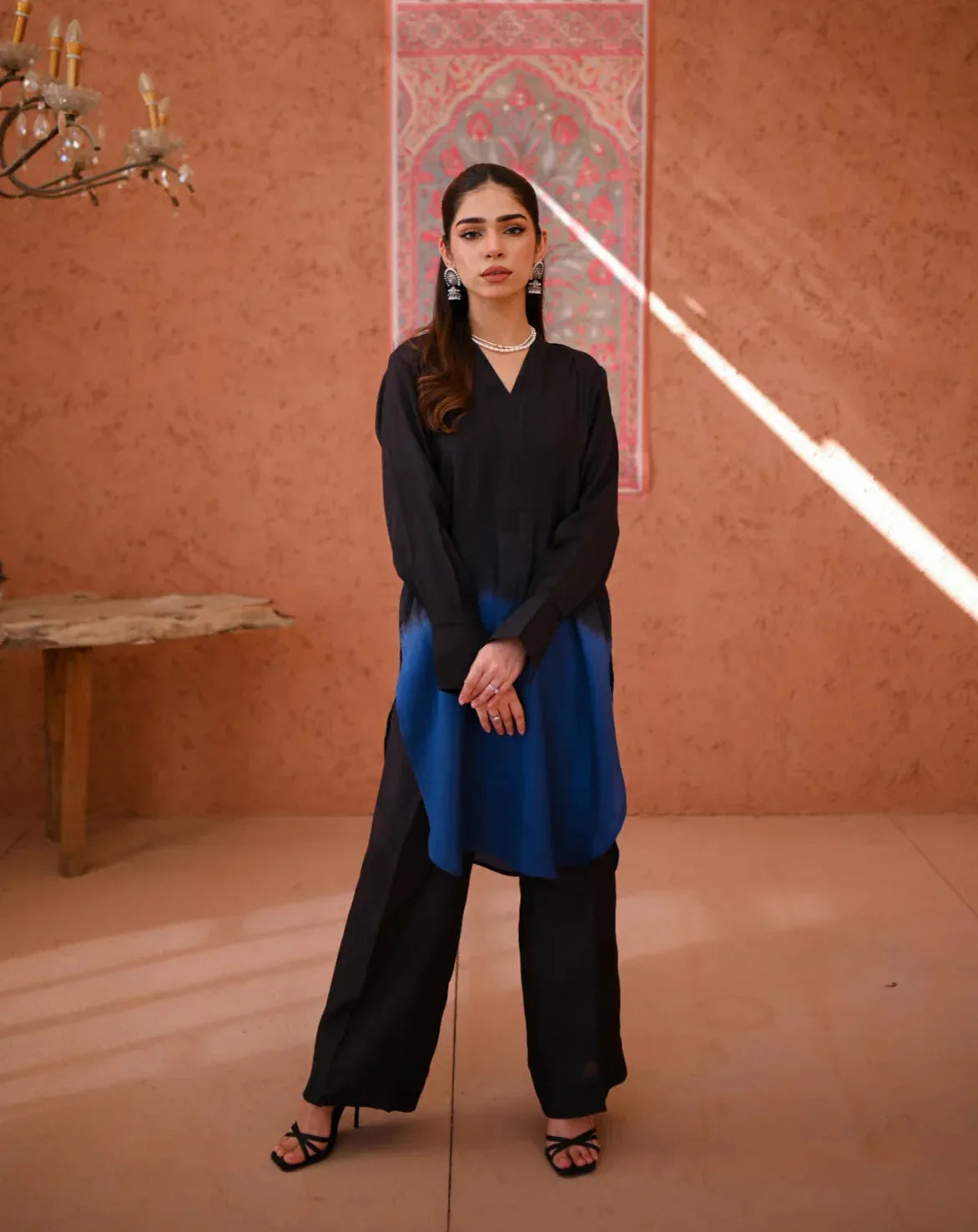 A woman wearing a two-piece Rawsilk dress with an Ombre shirt and culotte, standing in a room with earthen tones.