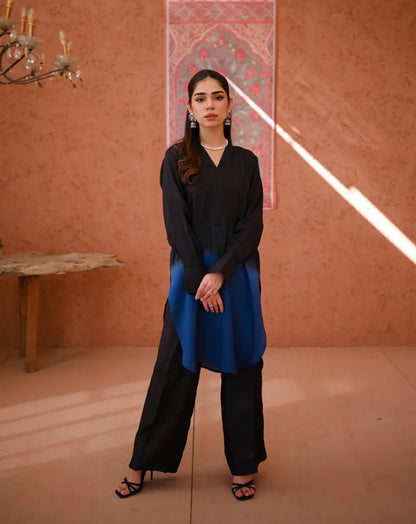 A woman wearing a two-piece Rawsilk dress with an Ombre shirt and culotte, standing in a room with earthen tones.