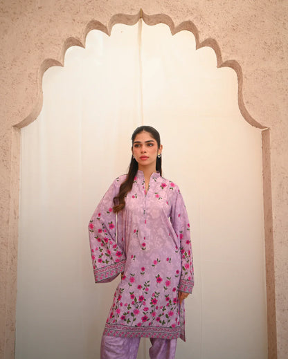 Woman wearing a pink floral outfit standing in front of an archway.