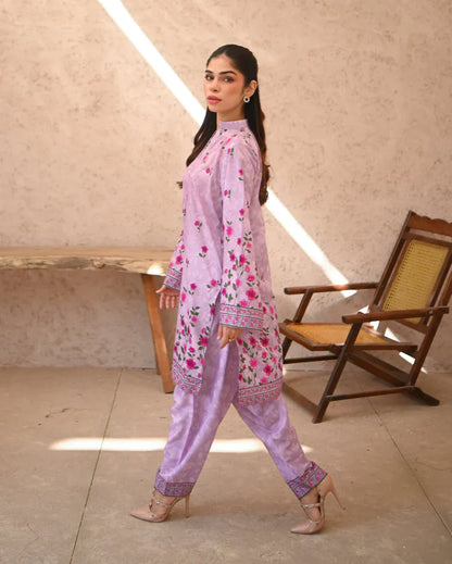 Woman wearing a pink floral printed dress which includes a shirt and shalwar.